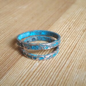 May include: Three stacked rings made of copper with a turquoise patina finish.