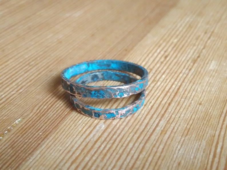 May include: Three stacked rings made of copper with a turquoise patina finish.