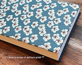 May include: A blue book with a white floral pattern on the cover. The book is closed and has a light brown spine.