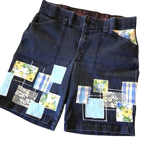 May include: Dark blue denim shorts with patchwork details. The patches are made of various fabrics, including floral prints, plaid, and lace. The shorts have a button fly and belt loops.