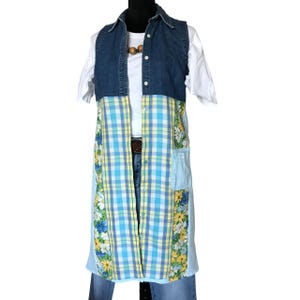 May include: A long denim vest with a plaid and floral print. The vest has a button-up front and a patch pocket on the right side.