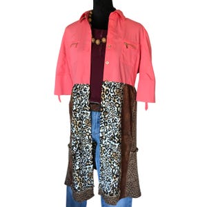 May include: A long, pink and brown patterned shirt with a button-up front and long sleeves. The shirt has a leopard print pattern on the bottom half and a solid pink color on the top half.