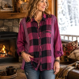 May include: A long-sleeve button-down shirt featuring a magenta and black plaid pattern on the front and back panels, contrasted by solid magenta side panels with vertical textured stripes, a small zippered chest pocket, and a frayed hemline.