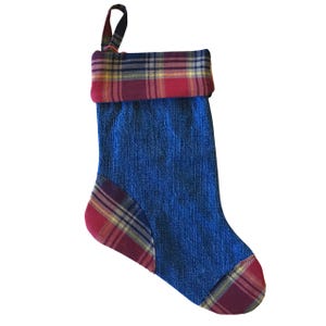 May include: A Christmas stocking made of blue denim fabric with red, yellow, and green plaid accents. The top cuff and toe are plaid, and a matching plaid loop is attached for hanging. The stocking is designed for holiday decor.