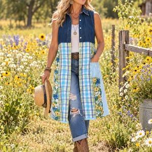 May include: A sleeveless duster vest featuring a dark blue denim bodice with a collar and button-down front, transitioning into a long, light blue and yellow plaid skirt panel with a floral print border and a single patch pocket on the side.