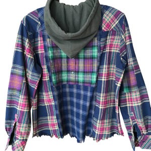 May include: A blue, green, pink, and white plaid flannel shirt with a green hooded sweatshirt attached to the collar.
