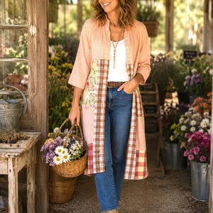 May include: A long-sleeved, button-down duster coat featuring a peach-colored gingham pattern on the upper section and sleeves, with contrasting patchwork panels in plaid and floral prints on the lower front, worn over a white top and blue jeans.