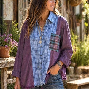 May include: A patchwork button-down shirt with a mix of purple, blue, and plaid fabrics. The shirt has long sleeves, a collared neckline, and a pocket on the chest. The model is wearing blue jeans and jewelry.