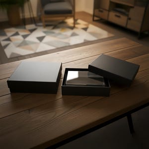 以下が含まれることがあります： 透明な長方形のガラス製の賞品が、木製のテーブルの上にある開いた黒い箱の中に展示されています。ふたが閉まった別の黒い箱が左側にあります。