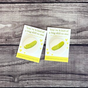 May include: Two white 1.25 inch button pins with a green pickle illustration and the text "You're kind of a big dill to me".