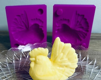 May include: Two purple silicone molds shaped like a rooster, with a yellow butter sculpture of a rooster in the center.