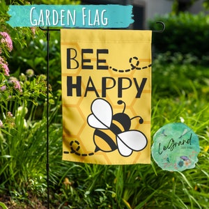 May include: Yellow garden flag with a bee and honeycomb pattern. The flag says "Bee Happy" in black text.