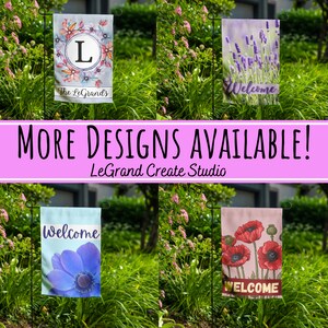 May include: Four different garden flags displayed on black metal poles. The flags are all 12x18 inches and feature various designs. The first flag has a watercolor floral design with the letter L in the center and the text "The LeGrands". The second flag has a purple lavender design with the text "Welcome". The third flag has a blue anemone design with the text "Welcome". The fourth flag has a pink poppy design with the text "WELCOME".
