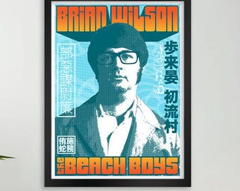May include: A framed poster featuring Brian Wilson with text that reads "Brian Wilson" and "The Beach Boys." The poster has a teal and orange color scheme with Japanese text. The poster is displayed above a beige couch with pillows and a blanket.