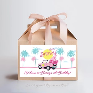 May include: A brown paper gift bag with a pink ribbon and a personalized label. The label features a pink flamingo on a pink and white truck with palm trees in the background. The text on the label reads "Maddie Britney Welcome to Britney's 8th Birthday!"