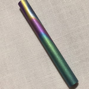 May include: A long, thin, iridescent pen with a metallic finish. The pen has a swirling pattern of yellow, purple, green, and blue.