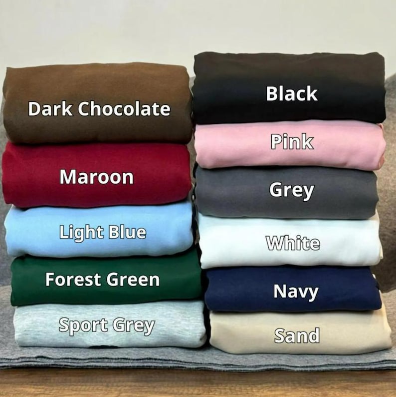 Puede incluir: Una pila de telas dobladas en varios colores, incluyendo chocolate oscuro, granate, azul claro, verde bosque y gris deportivo. Tambi&eacute;n incluye negro, rosa, gris, blanco, azul marino y arena. Cada color de tela est&aacute; etiquetado con su nombre.