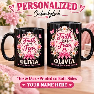 May include: Two black ceramic mugs in 11oz and 15oz sizes featuring a pink breast cancer awareness ribbon, floral wreath, and butterflies. The text reads Faith over Fear, Olivia, and Breast Cancer Awareness. Printed on both sides.