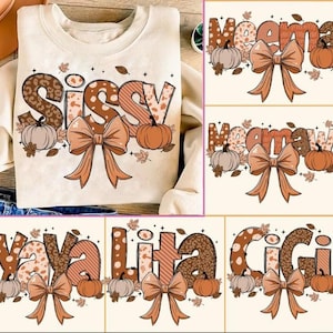 May include: A cream-colored crewneck sweatshirt featuring the word SISSY in large, patterned letters with brown leopard print and stripes. The design includes orange pumpkins, a large brown bow, and scattered autumn leaves in a fall theme.