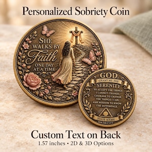 May include: Two round bronze-toned sobriety coins with raised relief designs. The larger coin features a woman walking toward a cross with butterflies and flowers, inscribed with "SHE WALKS BY FAITH ONE DAY AT A TIME." The smaller coin displays the Serenity Prayer.