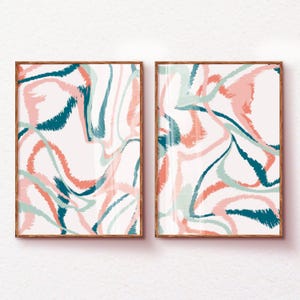 May include: Two framed abstract art prints with a white background and a swirling pattern of pink, teal, and blue brushstrokes.