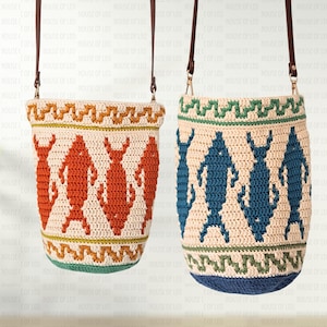 Puede incluir: Dos bolsos tipo cubo de ganchillo con correas de cuero marrón. El bolso de la izquierda es crema con motivos de peces naranjas y bordes en zigzag. El bolso de la derecha es crema con motivos de peces azules y bordes en zigzag verdes y azules.