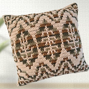 May include: A square crochet pillow cover featuring a geometric pattern in cream, olive green, and brown. The design consists of repeating leaf-like motifs arranged in vertical columns, separated by zigzag lines, creating a textured surface.