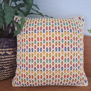 Può includere: Un cuscino quadrato all'uncinetto color crema con un motivo ripetuto di rettangoli verticali colorati. I rettangoli sono nelle tonalità di rosso, arancione, giallo, verde, blu e viola. Il cuscino misura circa 46 cm quadrati.