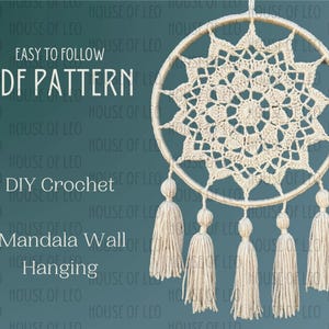 May include: A crochet mandala wall hanging with a beige color and a circular shape. The mandala has a starburst design with a fringe border. The hanging has five tassels at the bottom.