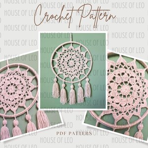 May include: A crochet dream catcher with a pink and white mandala design and white tassels. The dream catcher is hanging from a wooden hoop.