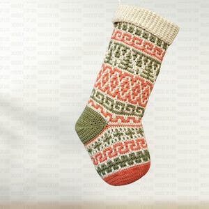 Può includere: Una calza di Natale fatta a mano con un polsino color crema e un motivo geometrico rosso, verde e crema. La punta e il tallone sono verdi e il fondo è rosso. La calza è fatta di filato.