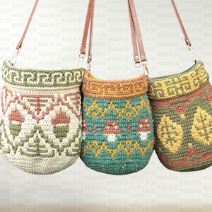 May include: Three handmade crochet bags with brown leather straps. The bags feature intricate geometric and nature-inspired patterns in shades of green, pink, yellow, and teal. The bags are suspended against a neutral background.
