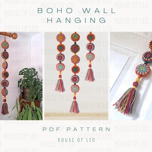 Puede incluir: Un tapiz de pared de ganchillo con estilo boho. El tapiz presenta una serie de círculos coloridos con un borla en la parte inferior. Los círculos son en tonos de naranja, amarillo, rojo y azul.