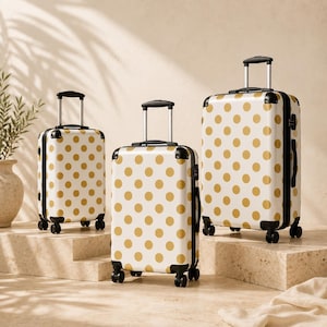 May include: A set of three upright suitcases in varying sizes, each featuring a white hard-shell exterior with a repeating pattern of gold polka dots. Each suitcase includes black corner protectors, a retractable handle, and four black spinner wheels.