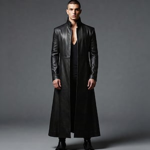 May include: A long, black leather coat with a high collar and a flowing, floor-length design. The coat is open in the front, revealing a black top. The coat's sleek silhouette and dark colour create a dramatic and stylish look.