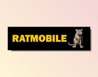 May include: A black rectangle with the word "RATMOBILE" in yellow letters. A gray rat is standing on the right side of the rectangle.