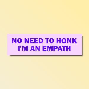 Può includere: Un adesivo rettangolare con la scritta "NO NEED TO HONK I'M AN EMPATH" in lettere viola su sfondo lilla chiaro. L'adesivo è posto su uno sfondo sfumato giallo e bianco.