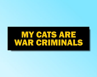 May include: Black bumper sticker with yellow text that reads "MY CATS ARE WAR CRIMINALS".