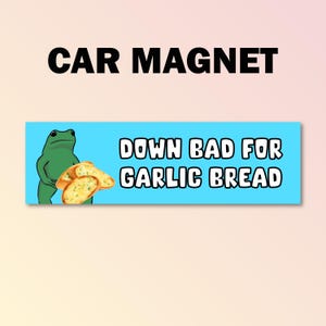 Könnte beinhalten: Ein Auto-Magnet mit hellblauem Hintergrund und dem Text "DOWN BAD FOR GARLIC BREAD". Ein Cartoon-Frosch in Grün ist links zu sehen und hält Knoblauchbrot. Über dem blauen Rechteck steht "CAR MAGNET".