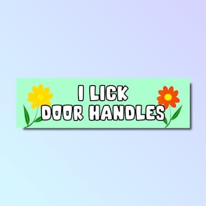 May include: A light green bumper sticker with the text "I lick door handles" in white bold letters. The sticker is decorated with two cartoon flowers, one yellow and one orange.