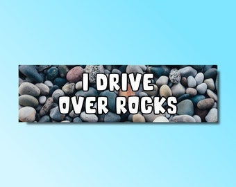 May include: A close-up of a rock-covered surface with the text "I drive over rocks" in white letters.