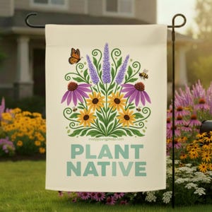 Puede incluir: Una bandera de jardín color crema con un diseño floral que incluye girasoles, equináceas moradas y lavanda. También se incluyen una mariposa y una abeja. Las palabras "PLANT NATIVE" están impresas en verde azulado.