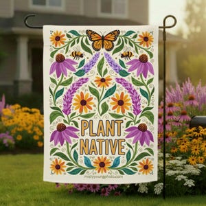 Puede incluir: Una bandera de jardín con un diseño floral que presenta una mariposa, abejas y el texto "PLANT NATIVE". La bandera tiene un fondo crema con elementos florales naranjas, morados y verdes. La bandera se muestra en un jardín.