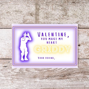 May include: A purple and gold Valentine's Day card with a white silhouette of a video game character. The card reads "Valentine, you make my heart griddy, your friend."