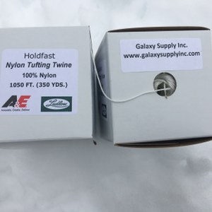 May include: A white box of Holdfast Nylon Tufting Twine, 100% Nylon, 1050 feet (350 yards). The box has a label with the company logo and product information. The twine is white and is visible through a small opening in the box.