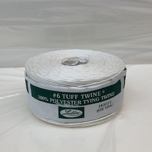May include: A white spool of #6 Tuff Twine, a 100% polyester tying twine, made by Ludlow. The spool is labeled with the product name, material, and length: 1830 ft (610 yds).