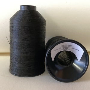 May include: Two spools of black thread, one on a plastic spool and the other on a cardboard spool.