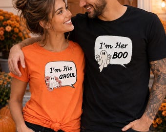 May include: An orange t-shirt with a graphic of a ghost and the text I'm His GHOUL and a black t-shirt with a graphic of a ghost and the text I'm Her BOO. Both shirts feature speech bubble designs with ghost illustrations and text printed on the front.