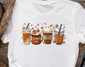 Puede incluir: Camiseta blanca con un diseño colorido de cuatro bebidas temáticas de otoño. Las bebidas incluyen un latte de especias de calabaza, una taza de especias de calabaza, una taza con estampado de leopardo y una taza llena de calabazas. La frase "PUMPKIN SPICE" está impresa en la taza.