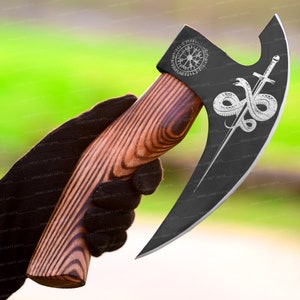 May include: A black axe with a wooden handle. The axe head has a design of a snake wrapped around a sword and a compass with runes.